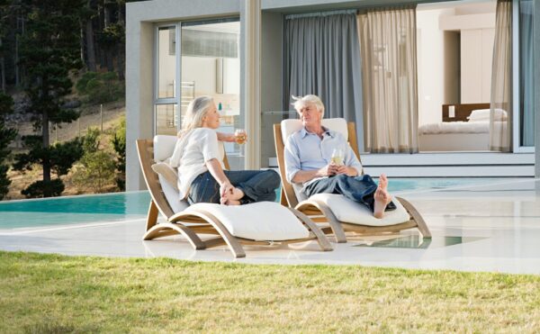 Middle aged couple relaxing on deck chairs by the pool