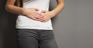 a young woman with bellyache or menstrual cramps holding her stomach.