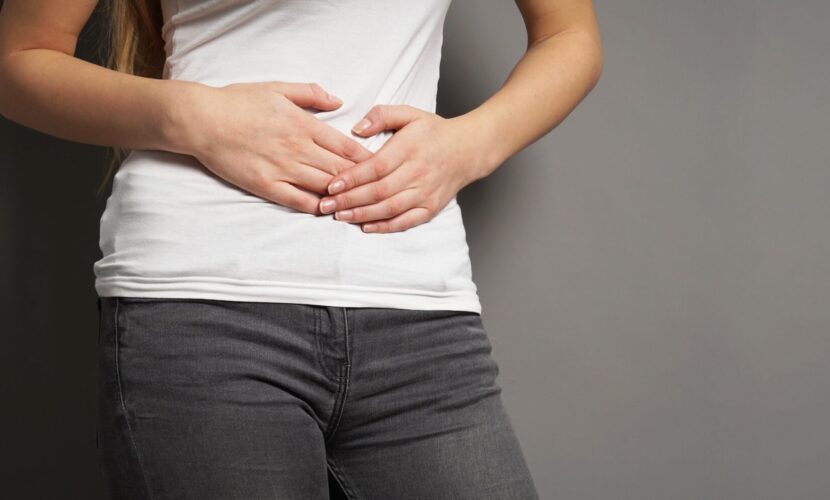a young woman with bellyache or menstrual cramps holding her stomach.