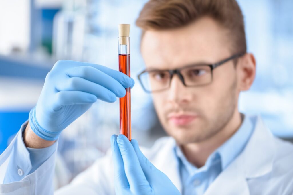 Man scientist in protective gloves holding test tube with reagent