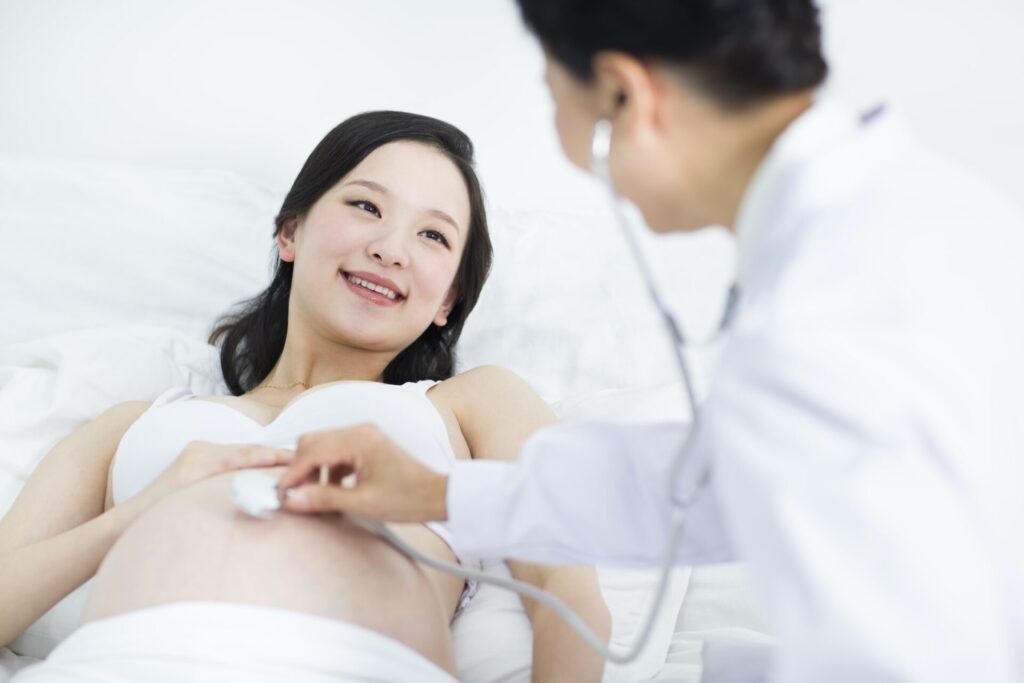 Doctor examining pregnant woman at home