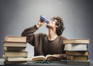 Young man studying and drinking energy drink.